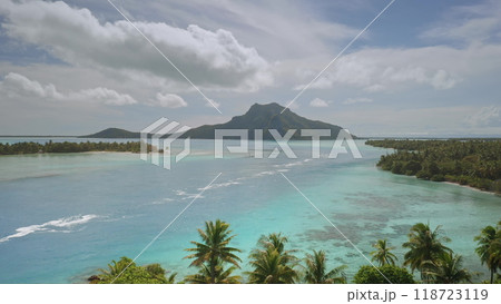 Aerial drone footage of turquoise lagoon waters separating lush islets from volcanic mount Teurafaatiu on tropical Maupiti island. French Polynesia remote wild nature exotic summer travel background 118723119