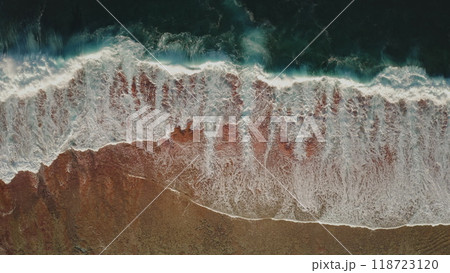 Dramatic ocean landscape background. Aerial view dark green ocean waves crashing on beautiful orange sand beach. Powerful water foam waves break wash coastline. Tropic nobody nature seascape. Top down 118723120