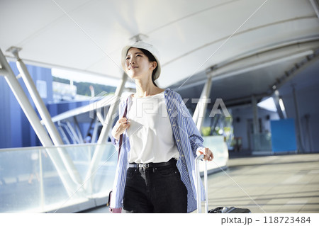 空港の連絡通路でスーツケースを引く女性旅行者の全身 空港の連絡通路でスーツケースを引く女性旅行者の全身 118723484