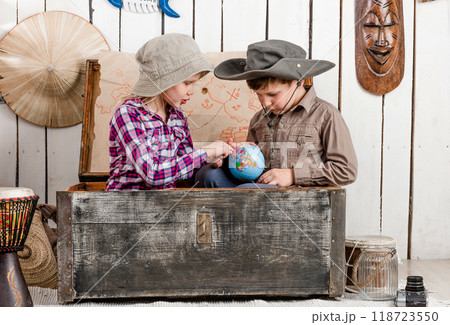 little boy and girl study globe sitting in big old chest little boy and girl study globe sitting in big old chest 118723550