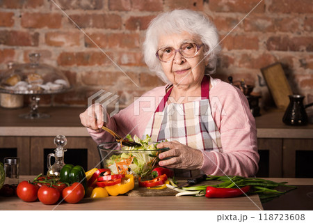 Senior woman cooking vegetable salad at the kitchen at home 118723608