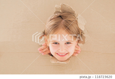 Smiling little girl peeping from hole in cardboard box 118723620