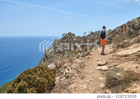 Intrepid Male Traveler Conquering Challenging Coastal Hiking Trail Amidst Dramatic Rocky Landscape and Turquoise Waters 118723930