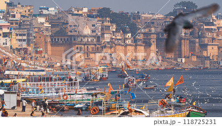 Varanasi, Uttar Pradesh, India. Many Boats are moored to the Ganga riverbank. Tourists boarding for an overnight boats ride on the Ganges River. Cityscape of Varanasi is visible - embankment in the Varanasi, Uttar Pradesh, India. Many Boats are moored to the Ganga riverbank. Tourists boarding for an overnight boats ride on the Ganges River. Cityscape of Varanasi is visible - embankment in the 118725231