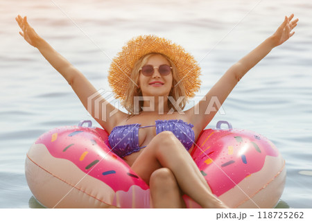 Beautiful young woman with inflatable donut in blue sea Beautiful young woman with inflatable donut in blue sea 118725262