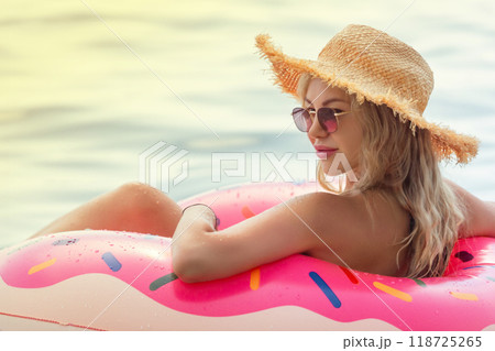 Beautiful young woman with inflatable donut in blue sea Beautiful young woman with inflatable donut in blue sea 118725265
