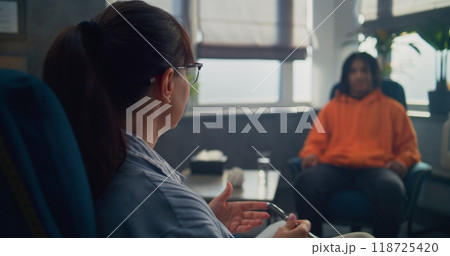 Back view of female psychologist providing therapy for African American teenager Back view of female psychologist providing therapy for African American teenager 118725420