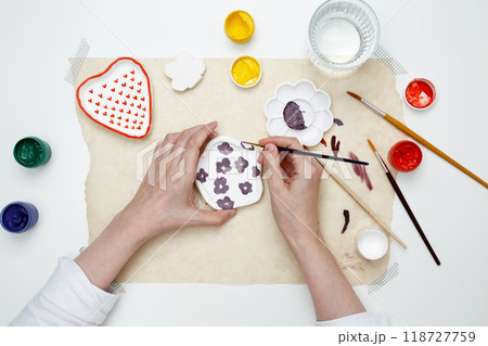 A woman paints clay products. Hobby clay modeling 118727759
