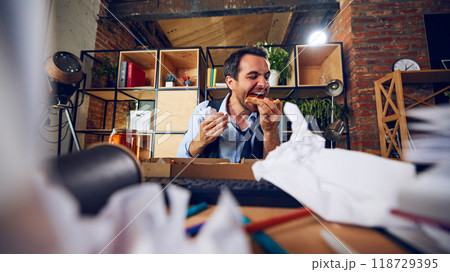 Worker eating with grin, oblivious to work chaos around him. His expression reveals lack of concern for consequences of his behavior. 118729395