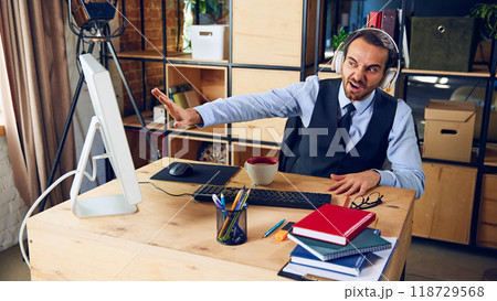 Frustrated and gesturing toward screen, he raises his hand as if to halt flood of tasks or an unwanted distraction during his work session. 118729568