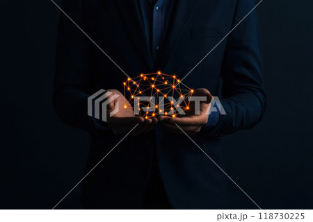 A person in a suit holds a glowing network of connections, symbolizing technology and innovation in a dark setting. A person in a suit holds a glowing network of connections, symbolizing technology and innovation in a dark setting. 118730225