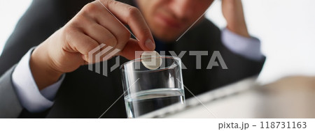 Tired man put tablet in glass with water to stop headache because of big workload Tired man put tablet in glass with water to stop headache because of big workload 118731163