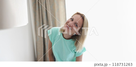 Happy smiling blonde young woman in apartment posing on curtain 118731263