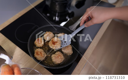 Meat balls beginning to fry in oil in frying pan on kitchen stove 118731310
