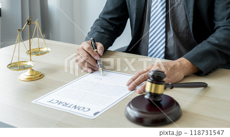 Lawyer hand holding pen and providing legal consult business dispute service at the office with justice scale and gavel hammer 118731547