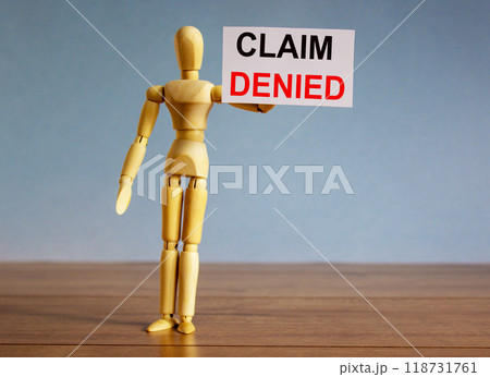 Wooden model of a man holding a tablet saying claim denied. Wooden model of a man holding a tablet saying claim denied. 118731761