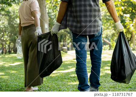Hand holding plastic bottles waste, Couple picking up trash putting to the black garbage bag at public Park on Environmental Earth day 118731767