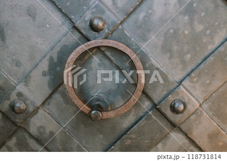 Close up of an iron old door knocker on a wooden front door of a house. 118731814