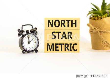 North star metric symbol. Concept words North star metric on wooden blocks on a beautiful white table white background. Black alarm clock. Business, finacial and north star metric concept. Copy space. 118731822