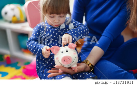 Cute little child putting coin cash into piggy bank container 118731911