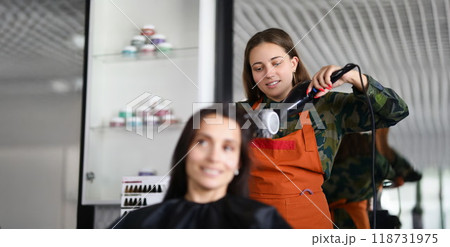 Smiling hairdresser using hairdryer for treatment with hair and being creative Smiling hairdresser using hairdryer for treatment with hair and being creative 118731975