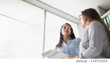 Female coworkers discussing report business growth and statistics 118732029
