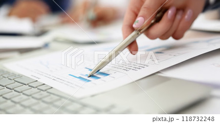 Man going through financial report paper with silver pen Man going through financial report paper with silver pen 118732248