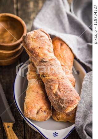 Crusty rustic baguette in bowl on wooden table. 118734327