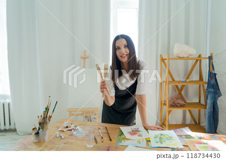 A Creative Artist is diligently at work in a bright and vibrant studio surrounded by stunning floral paintings 118734430