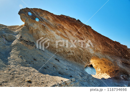 A rugged rock formation with a natural archway carved 118734698