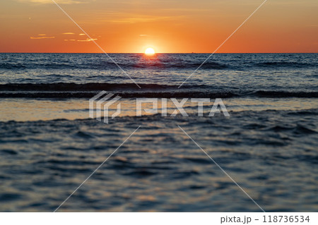 Sunrise. Dawn. Dawn in the sea. Sunrise in the sea. The first rays of sunlight rising through the sea water leaving a colorful, orange sky. Sun rays reflected in the waves of the sea. 118736534