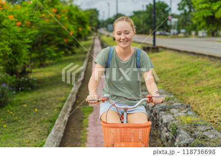 Female tourist cycling through the charming village of Bacalar, Mexico. Quintana Roo travel, scenic bike paths, and eco-friendly exploration concept Female tourist cycling through the charming village of Bacalar, Mexico. Quintana Roo travel, scenic bike paths, and eco-friendly exploration concept 118736698