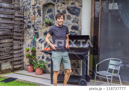 Man cooking dinner on a barbecue in his backyard. Outdoor cooking, home lifestyle, and family time concept 118737777