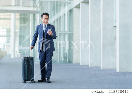 空港でスマートフォンを使う中高年のビジネスマン 空港でスマートフォンを使う中高年のビジネスマン 118738413
