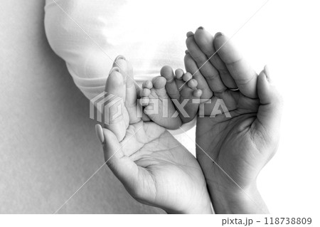 The palms of the parents. A father and mother hold the feet of a newborn child in a blanket. The feet of a newborn in the hands of parents. Black and white Photo of foot, heels and toes The palms of the parents. A father and mother hold the feet of a newborn child in a blanket. The feet of a newborn in the hands of parents. Black and white Photo of foot, heels and toes 118738809