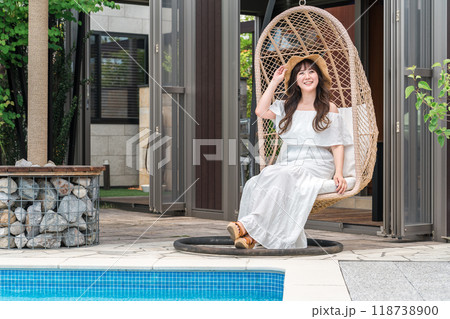 バカンスでプールサイドでハンギングチェアに座る若いアジア人女性(リゾート・ヴィラ・リラックス) バカンスでプールサイドでハンギングチェアに座る若いアジア人女性(リゾート・ヴィラ・リラックス) 118738900