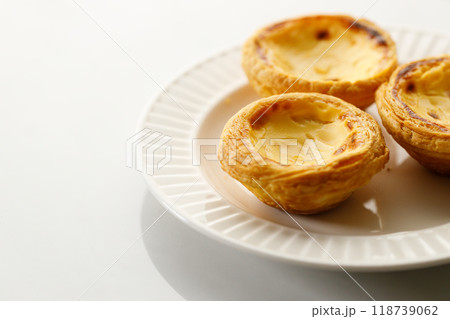 Stack of Portuguese sweet dessert egg tart or Pastel de Nata on white ceramic plate on white table. Copy space. Selective focus. 118739062