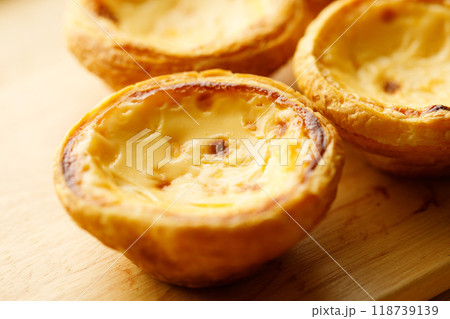 Stack of Portuguese sweet dessert egg tart or Pastel de Nata on wooden board on wooden table. Selective focus. Stack of Portuguese sweet dessert egg tart or Pastel de Nata on wooden board on wooden table. Selective focus. 118739139
