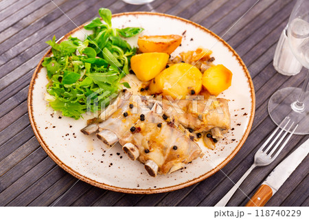 Appetizing grilled pork ribs with vegetable side dish of roasted potatoes garnished with greens and salad. Spanish cuisine Appetizing grilled pork ribs with vegetable side dish of roasted potatoes garnished with greens and salad. Spanish cuisine 118740229
