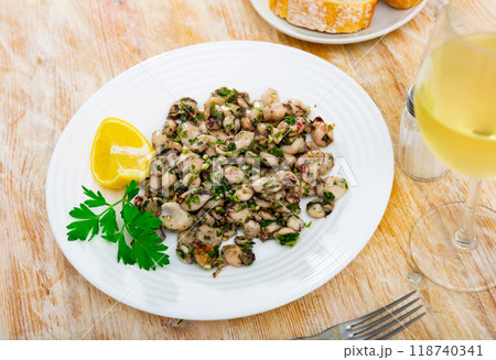There are pieces of grilled squid on plate. Seafood is complemented with lemon and parsley There are pieces of grilled squid on plate. Seafood is complemented with lemon and parsley 118740341