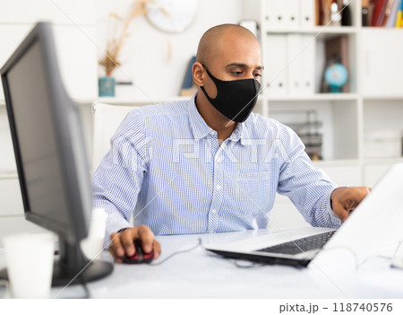 Coronavirus.Man with face mask working at computer during coronavirus epidemic. Prevention of COVID-19 infection Coronavirus.Man with face mask working at computer during coronavirus epidemic. Prevention of COVID-19 infection 118740576