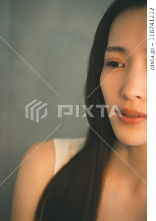 暖色の光を浴びて寂しそうに微笑む若い女性 暖色の光を浴びて寂しそうに微笑む若い女性 118741212