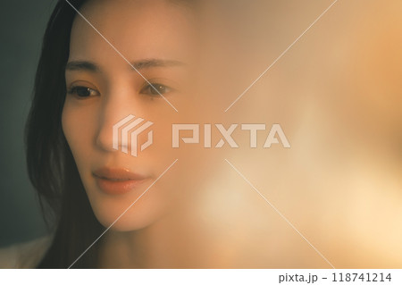 暖色の光を浴びて寂しそうに佇む若い女性 118741214