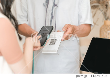 スマホでQRコード決済・スマホ決済・バーコード決済・オンライン決済・電子決済で会計する女性客 118741426