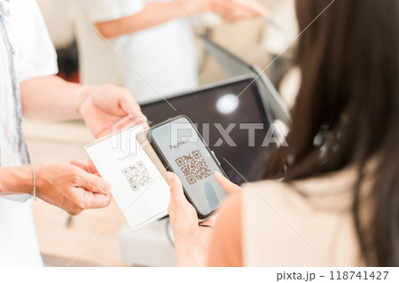 スマホでQRコード決済・スマホ決済・バーコード決済・オンライン決済・電子決済で会計する女性客 118741427