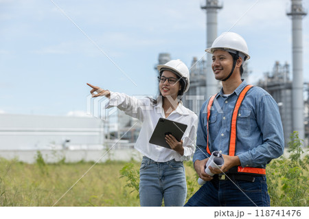 Engineer with blueprint and tablet working factory producing electricity oil energy. Engineer with blueprint and tablet working factory producing electricity oil energy. 118741476