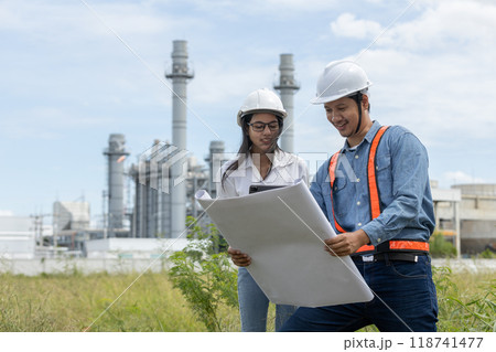 Engineer with blueprint and tablet working factory producing electricity oil energy.  118741477