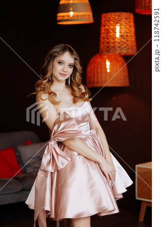 Woman in pink dress posing in Christmas interior with wooden furniture. 118742591