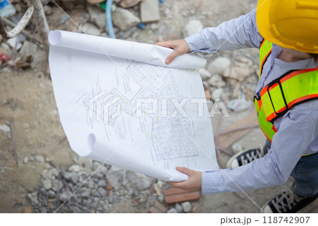 Female worker with blueprint working standing in construction site. Female worker with blueprint working standing in construction site. 118742907