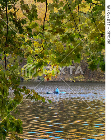Man Paddleboarding in Autumn Lake 118745796